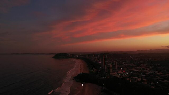 Aerial circle around over Miami headland with golden orange sunset sky, Gold Coast Australia