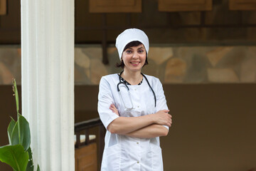 Female doctor with a beautiful smile in a work coat, full-length portrait.