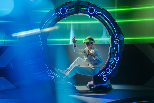 Woman wearing virtual reality simulators sitting in futuristic circle