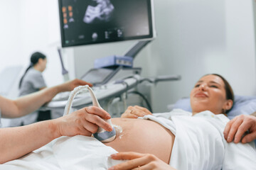 Smiling, medical procedure. Pregnant woman is lying down in the hospital, doctor does ultrasound