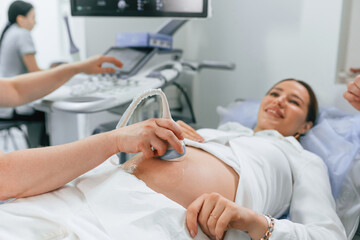 Smiling, medical procedure. Pregnant woman is lying down in the hospital, doctor does ultrasound