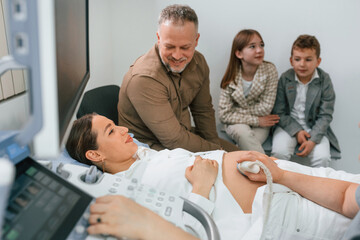 Obraz premium Man and kids. Pregnant woman is lying down in the hospital, doctor does ultrasound