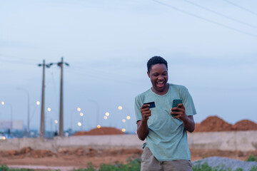happy african youth using his phone and credit card to make payment online. Buying and shopping...