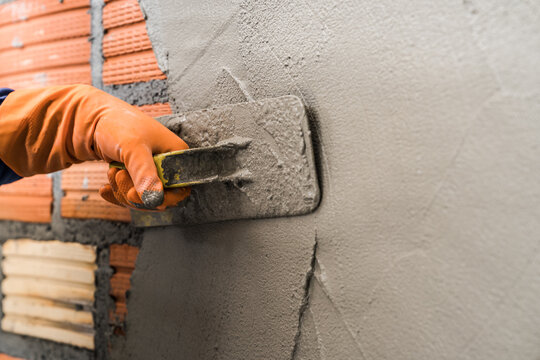 Hand worker plastering cement wall background interiors 