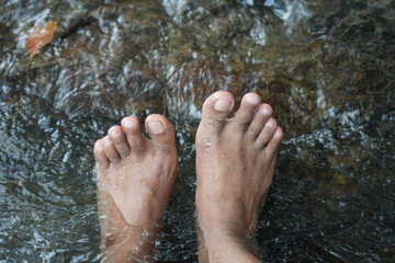 A man's feet being immersed in river water
