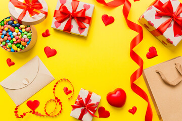 top view photo of st valentine day decor shopping, bag, envelope, gift, box, candy and red heart on colored background with empty space. Frame background