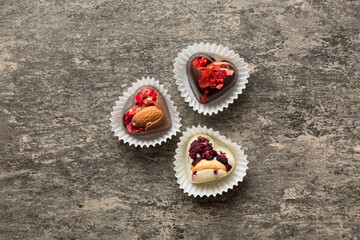 chocolate sweets in the form of a heart with fruits and nuts on a colored background. top view with space for text, holiday concept