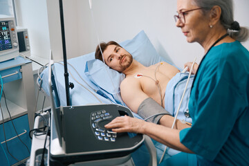 Obraz premium Experienced female specialist diagnostician makes a cardiogram to young patient