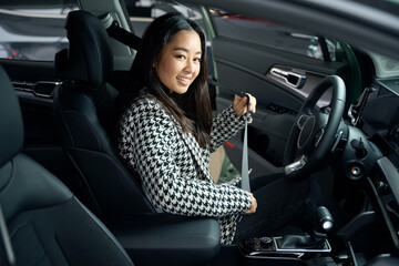 Obraz na płótnie Canvas Young asian woman sits in the drivers seat