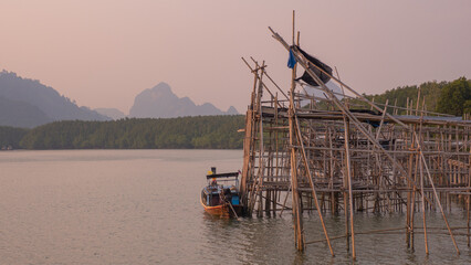 Fototapeta premium seaside port Fishermen use it to rest their boats in their ways. in a beautiful quiet setting Blue-green water and fresh green mangrove trees There is an indigo mountain backdrop.