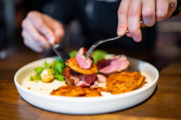 man with a knife and fork cuts grilled duck meat