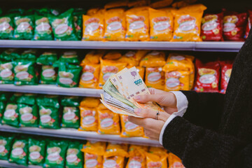 Woman counting money -Argentine pesos- in the supermarket.