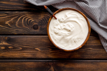 White sauce sour cream or yogurt in wooden bowl, top view