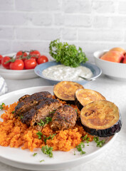 Greek plate with bifteki, served with tomato brown rice and fried eggplant on a plate
