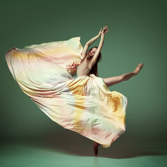 Portrait of charming ballerina, dancer wearing colorful dress over dark green background. Contemporary dance. Graceful jump © Lustre Art Group 