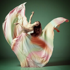 Portrait with one young girl, gorgeous ballerina wearing silk dress spinning in dance over dark green studio background © Lustre Art Group 