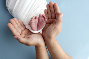 Tiny foot of a newborn baby. Soft legs of a newborn in a white blanket. Close up the toes, heels and feet of a newborn baby. Studio macro photography baby feet on a white background.