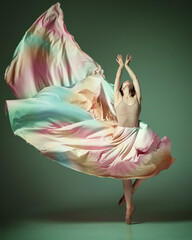 Charming ballerina dancing elegant, grace movement with flying fabric over dark green studio background. Rainbow dress © Lustre Art Group 