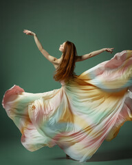 One young gorgeous ballerina, young girl dancing gracefully with with fabric over dark green studio background © Lustre Art Group 