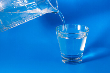 Pour the water from the jug into the glass.