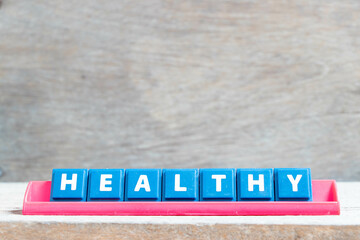 Obraz premium Tile alphabet letter with word healthy in red color rack on wood background