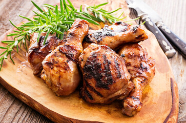 Traditional barbecue chicken legs and breast with hot chili marinade and herbs served as close-up on a rustic wooden board