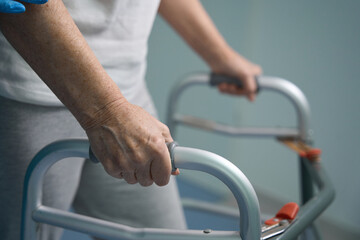 Fototapeta na wymiar Elderly patient moves with a walker along the hospital corridor