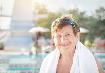 Active healthy senior (elderly) woman (over the age of 50) in sport goggles and with towel smiling...