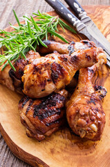 Traditional barbecue chicken legs and breast with hot chili marinade and herbs served as close-up on a rustic wooden board