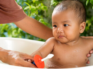 Mother teaching Asian baby 6 month old teeth brushing