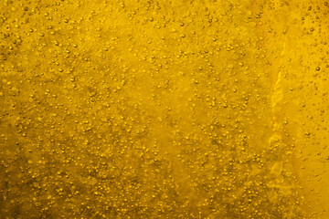 Air bubbles or bubbles of various sizes floating in a golden yellow liquid or gold background for use as wallpaper.