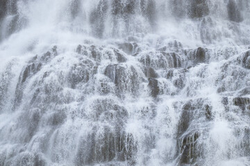 Fototapeta na wymiar Water Water Texture from Huge Waterfall. Powerful Mountain River Background. Beautiful Pure Nature in Iceland. Dynjandi Waterfall.