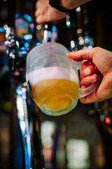 man bartender hand at beer tap pouring beer in glass in bar or pub