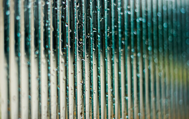 Window glass surface with a strip pattern in the rain. Shot in close up with selective focus. Great for background and pattern designs.