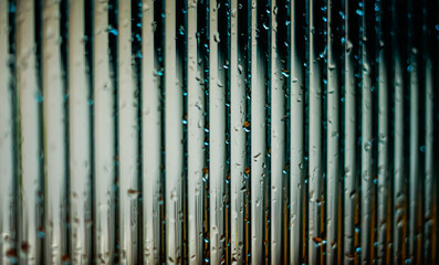 Window glass surface with a strip pattern in the rain. Shot in close up with selective focus. Great for background and pattern designs.