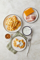 Snack waffles with bacon, cheddar cheese and dried fried onions and tzatziki sauce on light background