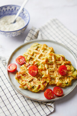 Snack waffles with bacon, cheddar cheese, spinach, sauce and cherry tomatoes on light background