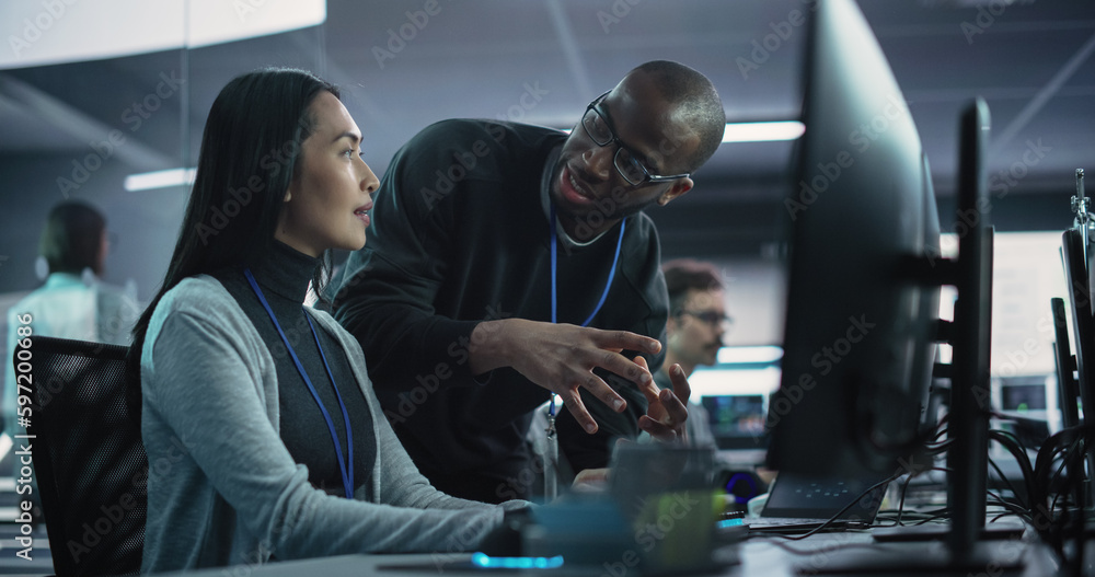 Poster Two Diverse Multiethnic Colleagues Having a Conversation While Busy Working on a Team Project. Asian Female Designer Talking with an African Project Manager. Teamwork in Technology Laboratory