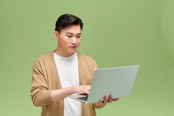 Smart young asian student using laptop isolated over green background