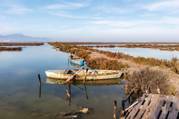 Sardinia, Italy, 2022 December - Old wooden rowing boat moored at the pier on the water.