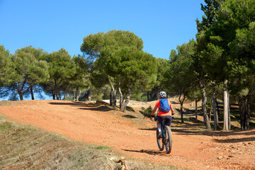 nice, active senior woman riding her electric mountain bike in the pine tree forests near Granada, Andalusia, Spain