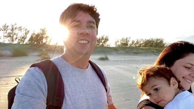 Family with father, mother and son walking along the beach on a winding day in the late afternoon as the sun goes down. Mention the relationship between parents and children and care for children.