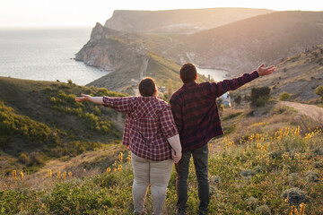 Tourists: a guy and a girl on top of a mountain watching a beautiful sunset. Travel and active life concept.