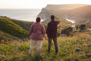 Tourists: a guy and a girl on top of a mountain watching a beautiful sunset. Travel and active life concept.