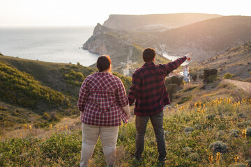Tourists: a guy and a girl on top of a mountain watching a beautiful sunset. Travel and active life concept.