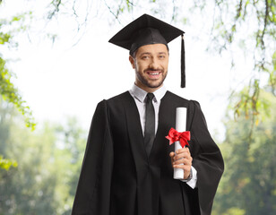Male graduate studend with a diploma standing outdoors