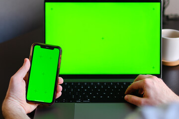 Information or data transfer between mobile phones and laptop, mockup or concept of wareless connection between apps. Adult male hand holding smartphone and texting on notebook. Copy space for text 