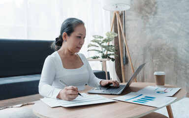 Confident asian chinese mature businesswoman working with laptop and desktop computer doing some...