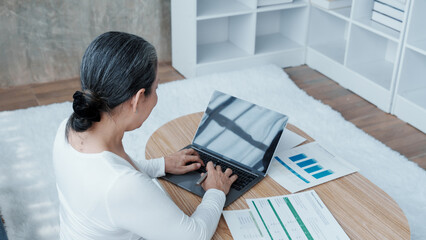 Confident asian chinese mature businesswoman working with laptop and desktop computer doing some...