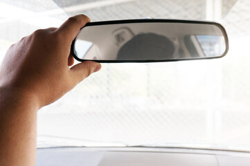 Man driver adjusting his rearview mirror in the car